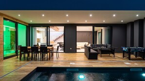 Uma área interna de piscina moderna com uma mesa de jantar e cadeiras, um sofá e uma mesa de pebolim.