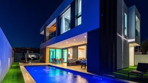 Uma casa moderna de dois andares com piscina, área de estar externa e interior bem iluminado.