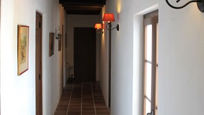 Un couloir doté d’un sol carrelé, de poutres en bois au plafond et de lampes fixées aux murs.