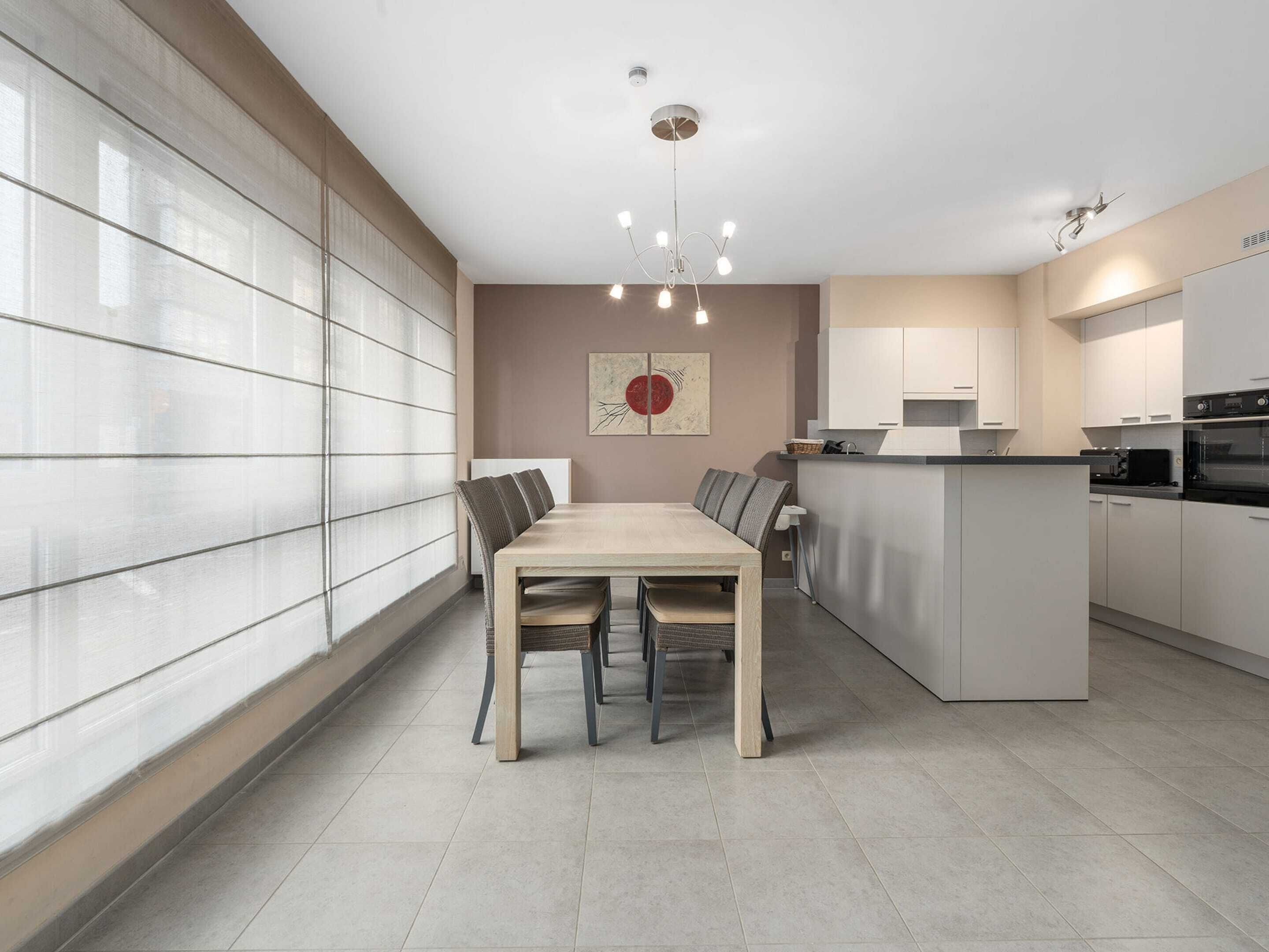 A modern kitchen with a dining area, large windows, and a central island.