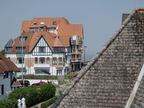 Ein mehrstöckiges Wohngebäude, das traditionelle und moderne Architekturstile vereint, mit einem markanten Giebeldach und mehreren Balkonen.