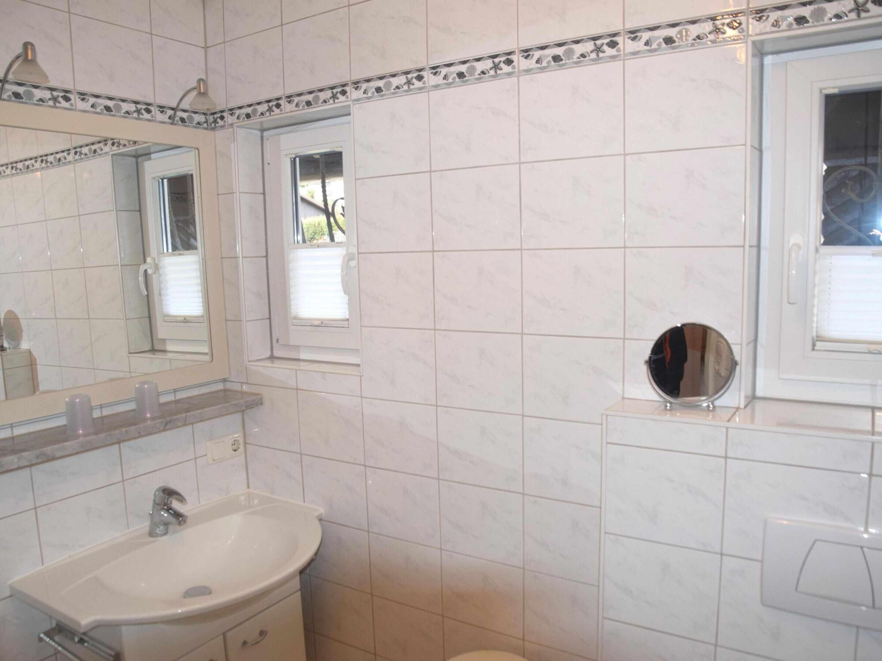 Ein Badezimmer mit Waschbecken, Spiegel und Fenster.
