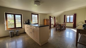 Cozinha espaçosa com ilha central, grandes janelas e área de refeições com cadeiras.