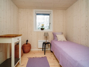 A room with a bed, a nightstand, a lamp, a window with a view, and a small table.