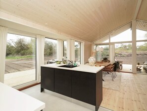 A modern kitchen with a large island, wooden flooring, and large windows offering views of the outdoors. - 5 Star Holiday Home in Horve (Follenslev)