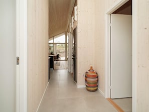 A hallway with wooden walls and a tiled floor leading to a room with a door. - 5 Star Holiday Home in Horve (Follenslev)