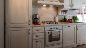 Una cocina con estufa a gas, cafetera y pileta.