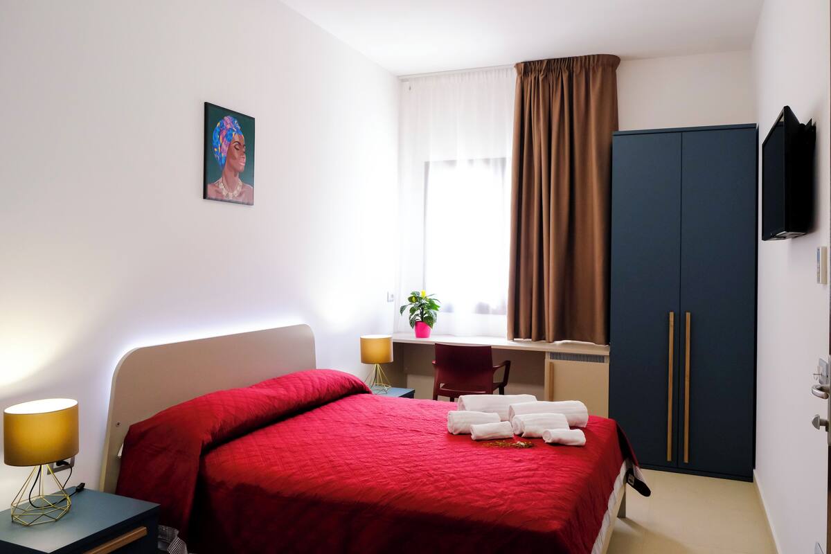 Ein Hotelzimmer mit einem Bett, einem Schreibtisch, einem Sessel, einem Fernseher und einem Kleiderschrank.