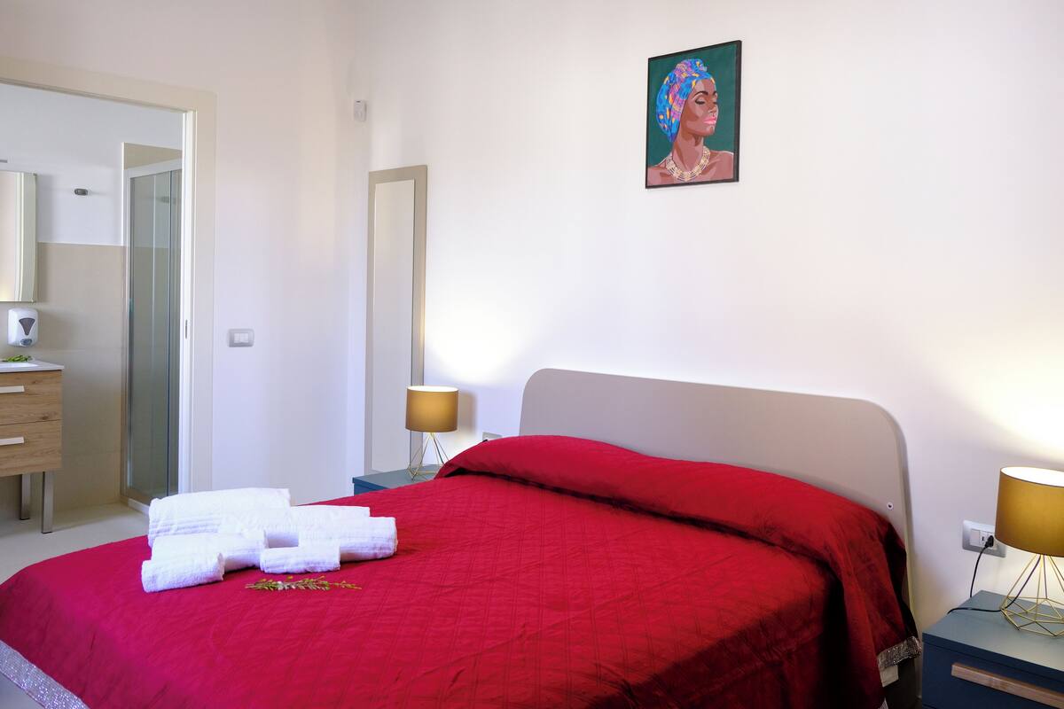 Ein Hotelzimmer mit einem Bett, einem Nachttisch mit Lampe, einer Kommode und einem Bild an der Wand.