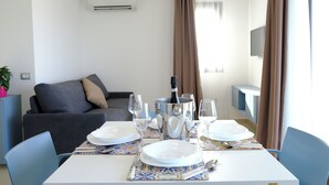 A dining area with a table set for two, a bottle of champagne, and a TV mounted on the wall. - Sol Y Mar Camere e Appartamenti (Castellammare del Golfo)
