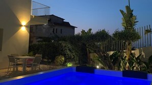 A swimming pool with a blue-lit deck, surrounded by a fence and vegetation. - Sol Y Mar Camere e Appartamenti (Castellammare del Golfo)