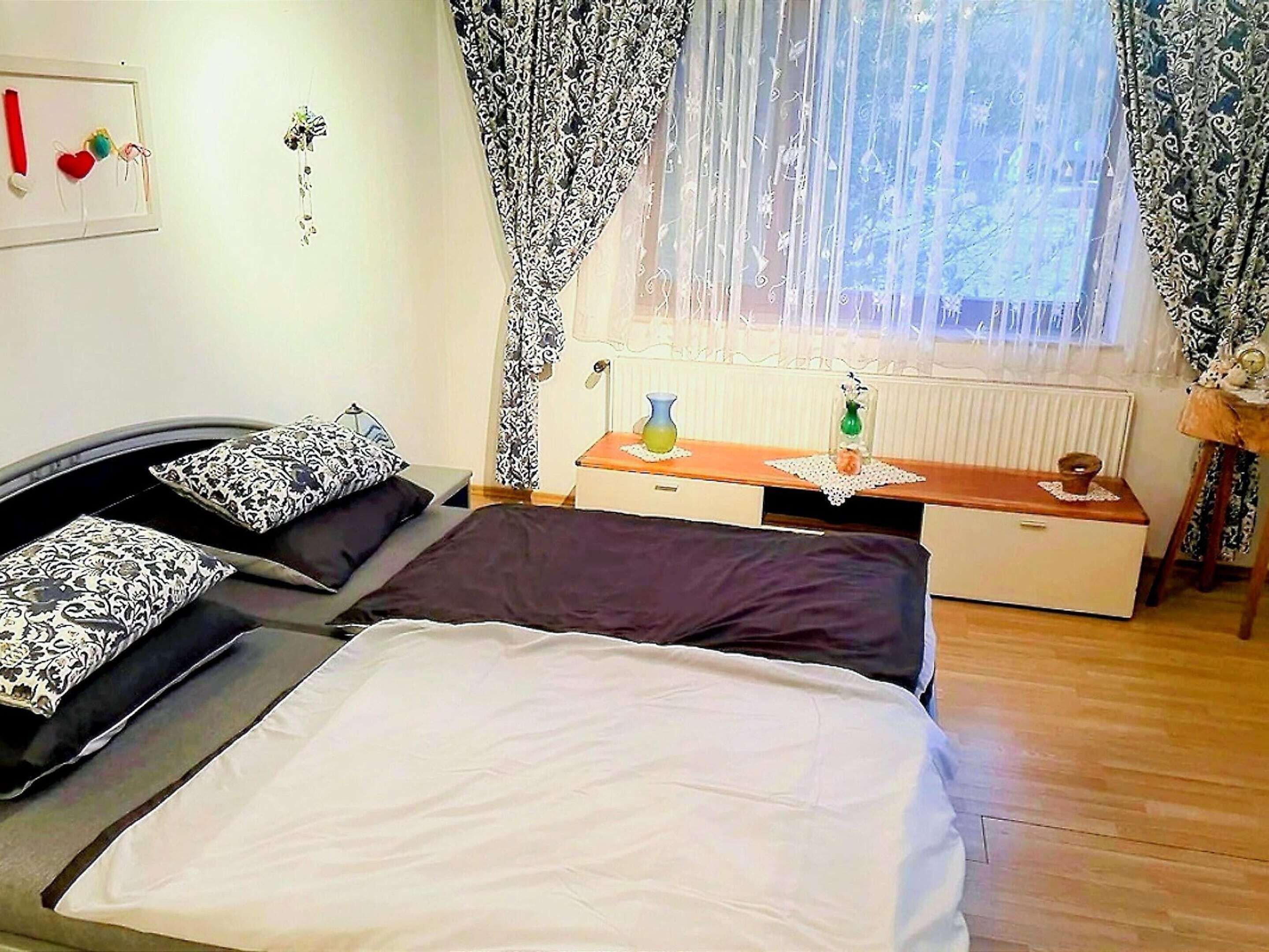 A bedroom with a bed, bedside table, and a window with curtains.