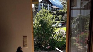 Habitación con puerta corrediza de vidrio que da a un espacio exterior con vista a un edificio y follaje.