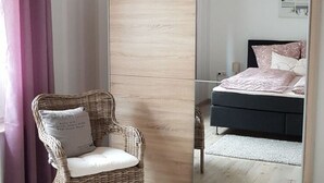 Un dormitorio con cama, una silla y un espejo.
