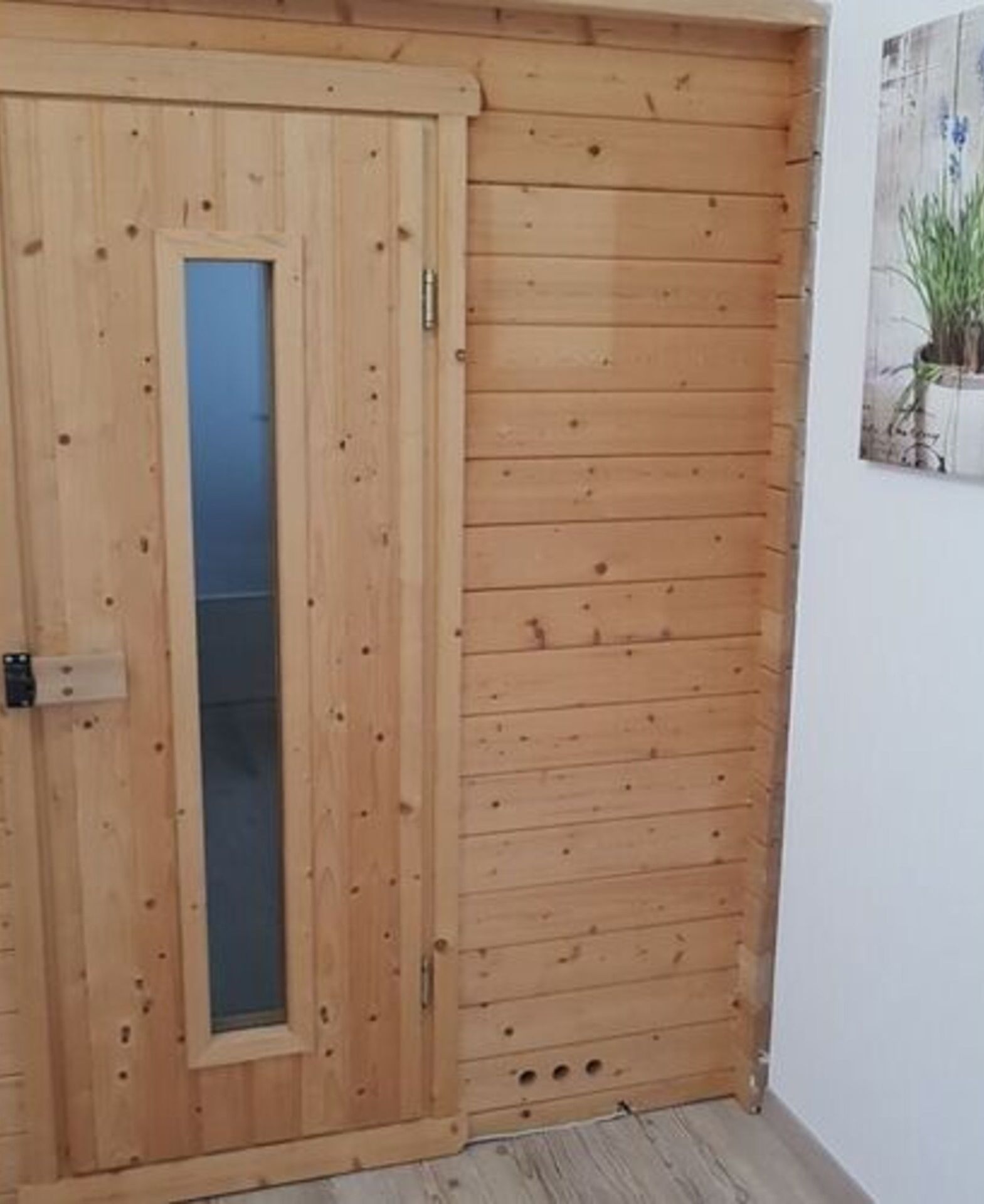 A wooden door with a glass panel and a small window, adjacent to a wall with a wooden panel design.