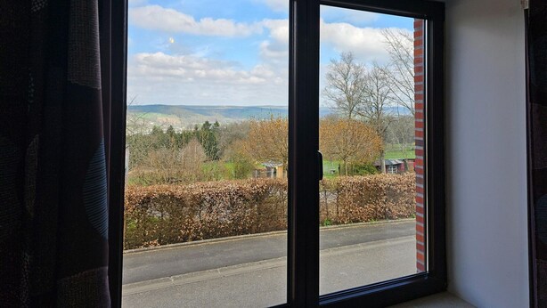 A room with a large window offering a view of a road, trees, and distant hills. - Well-equipped Holiday Home With Terrace (Stavelot)