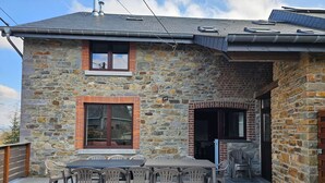 A stone house with a patio area featuring a table and chairs. - Well-equipped Holiday Home With Terrace (Stavelot)