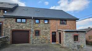 A two-story stone house with a garage, a small attached shed, and a paved driveway. - Well-equipped Holiday Home With Terrace (Stavelot)