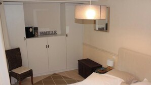 Une chambre à coucher comprenant un lit, une chaise, une armoire, une table de chevet et une lampe.