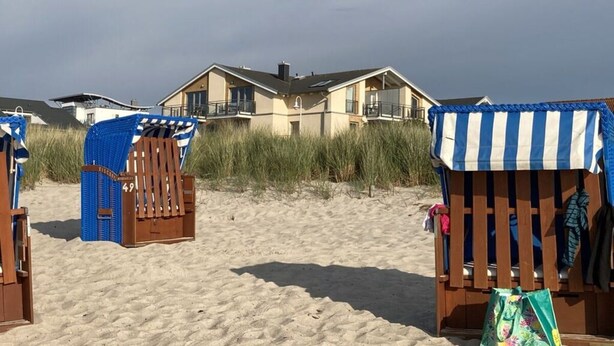 A beach with a large house in the background, surrounded by tall grass. - Beach Apartment With sea Views (Glowe)