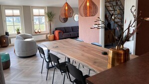 A modern kitchen with a wooden island, black chairs, and pendant lights. - Villa in Wieringer Near the Wadden Sea (Hippolytushoef)