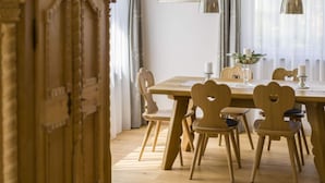 A dining area with a wooden table and chairs, a vase with flowers, and a framed picture on the wall. - Marlena Hollental Chalet (Garmisch-Partenkirchen)
