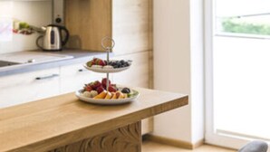 A kitchen with a wooden countertop, a fruit platter, and a kettle. - Marlena Hollental Chalet (Garmisch-Partenkirchen)