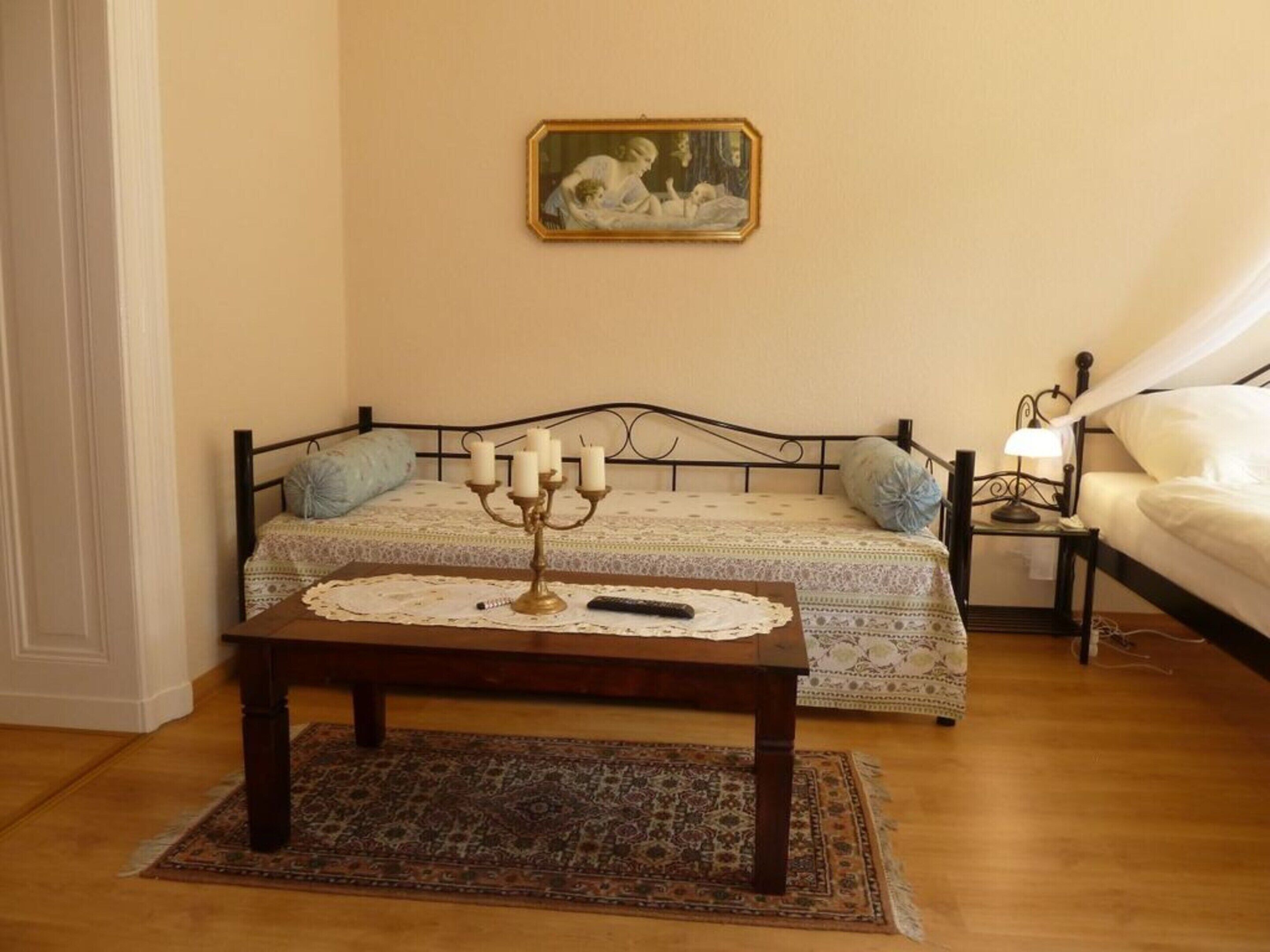 Una camera da letto con un letto, un comodino con una lampada, un candelabro, un quadro appeso al muro e un tappeto decorato.