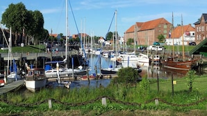 A marina with boats docked, a grassy area in the foreground, and buildings in the background. - Holiday Apartment Leah (Toenning)