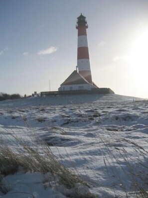 A lighthouse on a snowy hill with a clear sky. - Holiday Apartment Leah (Toenning)