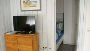 A room with a wooden cabinet, a television on top, a bed with striped bedding, and a painting on the wall. - Cosy Holiday Home With Garden (Titisee-Neustadt)