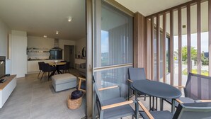 A modern living space with a kitchen, dining area, and a balcony with outdoor seating. - New-build Apartment Near the City Center (Middelkerke)