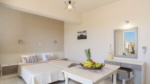 A hotel room with two beds, a dining table with fruit, a mirror, and a cityscape view. - Eugenia studios & apartments  (Rhodes)