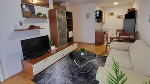 Ein kompakter Wohnraum mit Sofa, Fernseher, Esstisch und Küchenzeile.