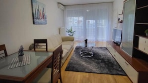 Ein modernes Wohnzimmer mit einem Glastisch, einer Couch, einem Fernseher und einem Gemälde an der Wand.