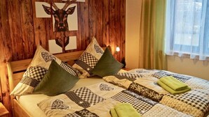 Un dormitorio acogedor con cabecera de madera, ropa de cama estampada y una decoración de cabeza de ciervo.