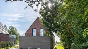 Ein modernes Haus mit geneigtem Dach, einem Backsteinsschornstein und einem großen Fenster.