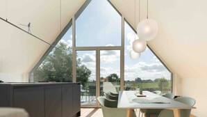 Eine moderne Küche mit einem großen Fenster, einem Essbereich mit Stühlen und Blick ins Freie.