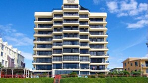 Um hotel de vários andares com fachada plana, várias janelas e um letreiro com a inscrição "Pelican Sands" no topo.
