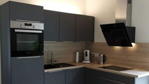Une cuisine moderne avec des meubles gris, un four encastré, un évier et une machine à café.