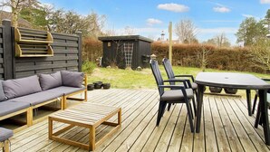 Una terraza de madera con sofá, sillas y una mesa.