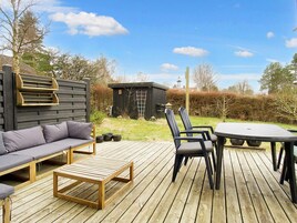 Una terraza de madera con sofá, sillas y una mesa.