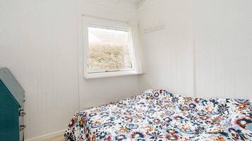 A bedroom with a bed, a window, and a wooden floor.