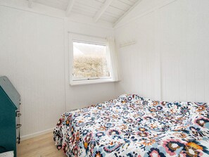 A bedroom with a bed, a window, and a wooden floor.