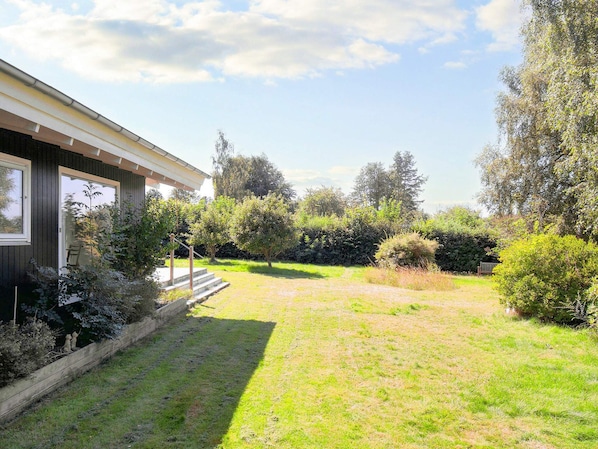 A residential property with a paved driveway, a wooden deck, and a well-maintained lawn. - 4 Person Holiday Home in Graested (Graested)