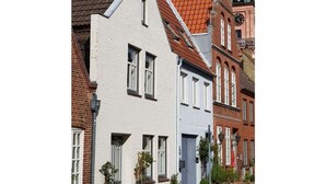 A traditional European building with a steeply pitched roof, white facade, and a visible clock tower in the background. - Haus Limosa Comfortable Holiday Residence (Friedrichstadt)
