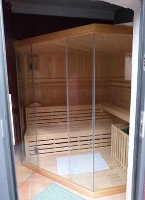 A sauna room with a wooden interior, a glass door, and a tiled floor. - Haus Limosa Comfortable Holiday Residence (Friedrichstadt)