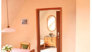 A room with a dining table, chairs, a dresser, and a mirror. - Holiday Apartment Erika Leonhardt (Dersau)