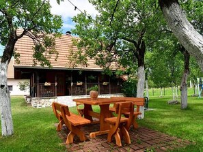A wooden table and benches set on a brick patio with a building in the background. - Holiday Home Tetina Kuca (Saborsko)