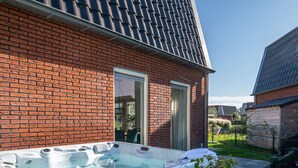 A brick house with a glass door and a hot tub in the backyard. - Spacious Holiday Home With Outdoor spa (Akkrum)